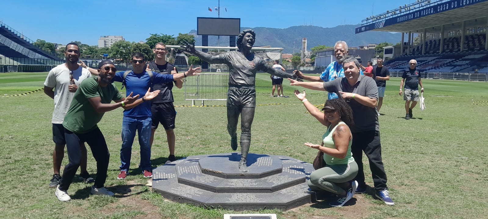 Grupo de turistas ao lado da estátua no gramado do Estádio de São Januário